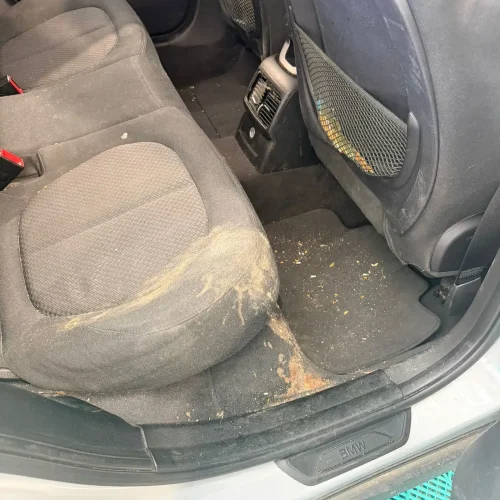 Silně znečištěná zadní sedačka a podlaha automobilu před čištěním